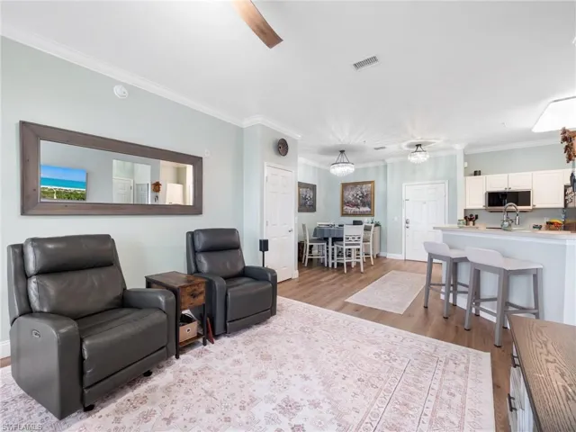 Living area with crown molding, light wood finished floors, and a ceiling fan