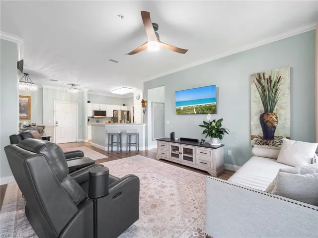 Living room featuring ornamental molding, a ceiling fan, and light wood finished floors
