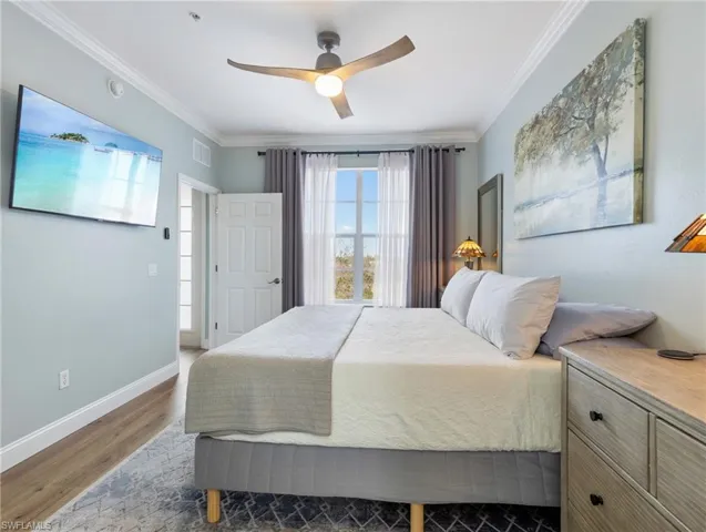 Bedroom with wood finished floors, crown molding, and a ceiling fan