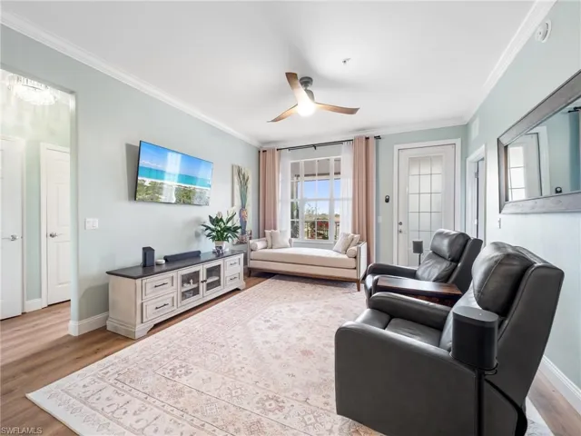 Living room with crown molding, light wood-style floors, and ceiling fan