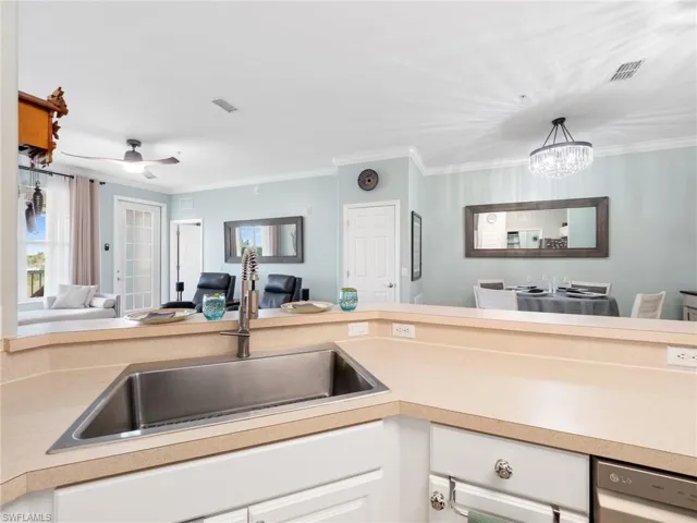 Kitchen featuring open floor plan, light countertops, crown molding, stainless steel dishwasher, and white cabinets