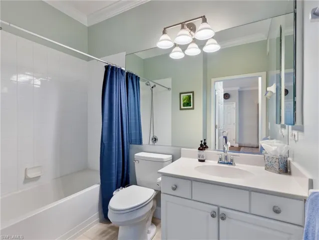 Bathroom with crown molding, vanity, and shower / tub combo