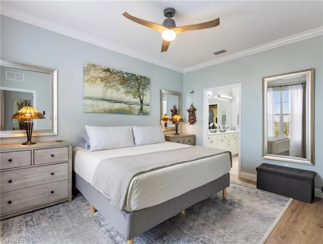 Bedroom featuring ornamental molding, ceiling fan, light wood-type flooring, and connected bathroom