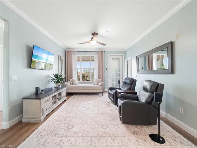 Living room featuring ornamental molding, light wood-style flooring, and ceiling fan