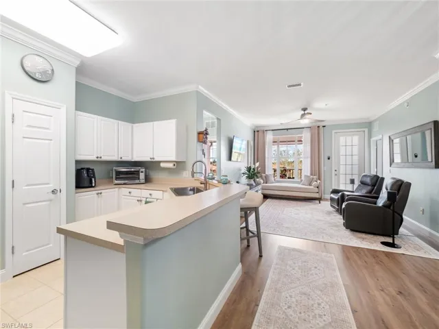 Kitchen with open floor plan, white cabinets, light countertops, a breakfast bar, and ornamental molding