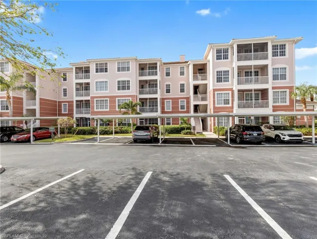 View of apartment building / complex featuring covered and uncovered parking