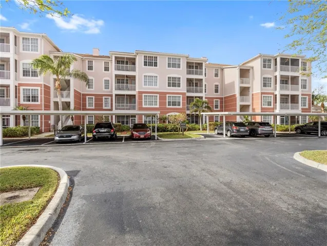 View of apartment building / complex featuring covered parking