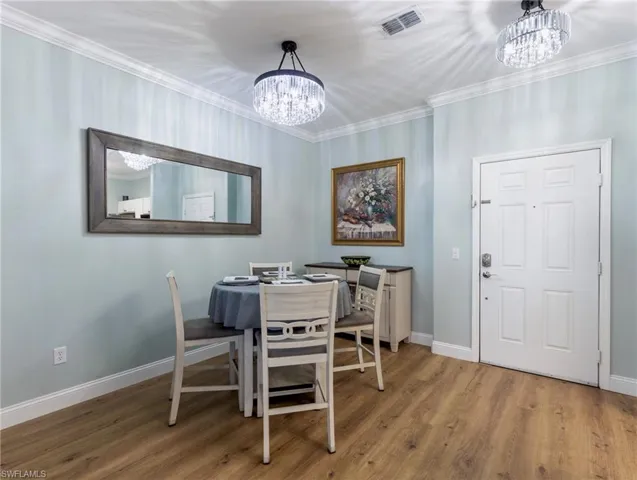 Dining space with a chandelier, light wood-style floors, and ornamental molding