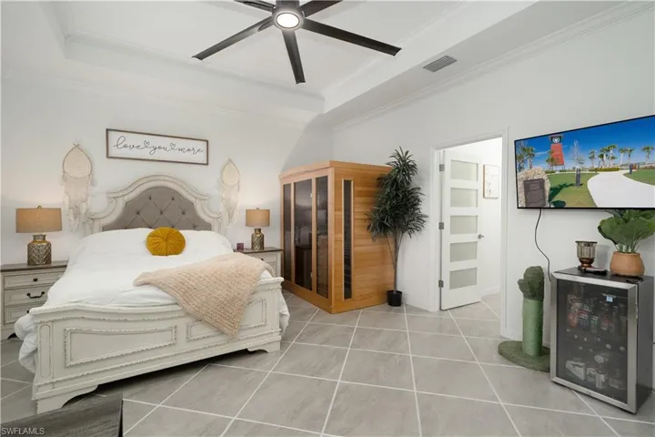 tray ceiling, crown molding, and ceiling fan for added comfort in the primary bedroom