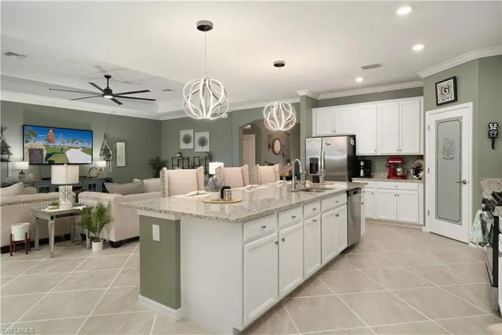 Kitchen featuring an island with sink, hanging light fixtures, white cabinets, and appliances with stainless steel finishes