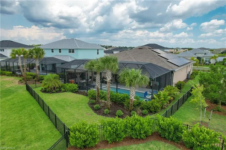 Rear view of property featuring a lanai, a yard, and a fully fenced in pool area