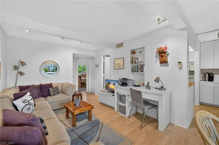 Living area featuring light wood-finish flooring, recessed lighting, and a built-in desk with shelving