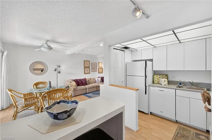 Kitchen with white cabinetry and appliances, wood-finish flooring, and track lighting