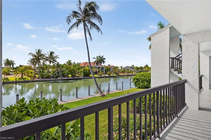 Waterfront balcony with a metal railing, overlooking a canal with boat docks