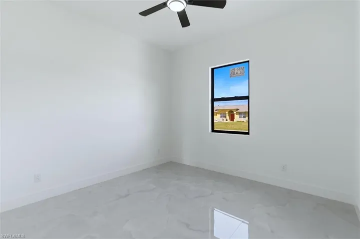Spare room featuring light marble finish floors and a ceiling fan
