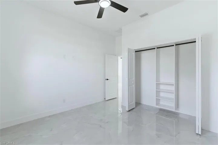 Unfurnished bedroom featuring a closet, a ceiling fan, and light marble finish floors