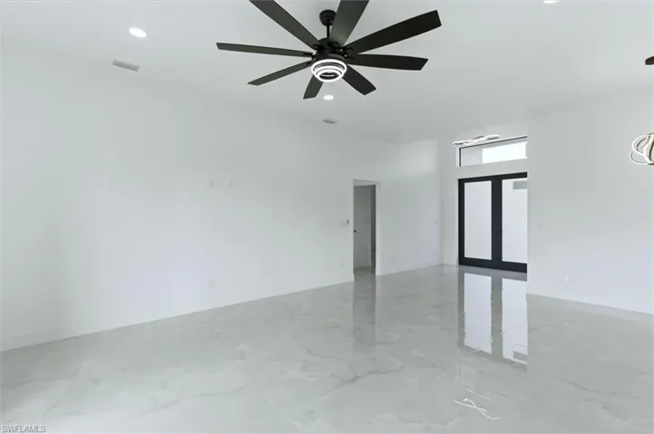 Empty room with french doors, ceiling fan, recessed lighting, and light marble finish flooring