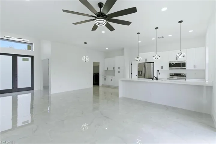 Unfurnished living room featuring a ceiling fan, recessed lighting, light marble finish flooring, and french doors