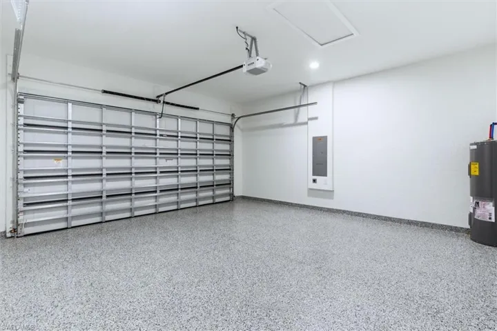 Garage featuring water heater, electric panel, and a garage door opener