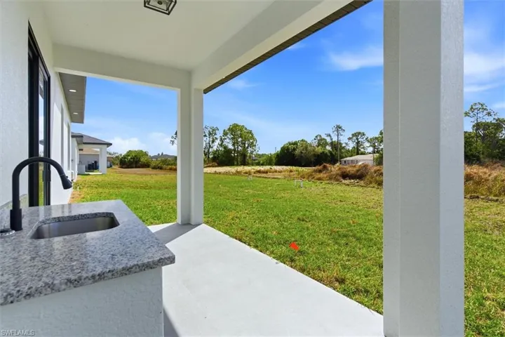 View of green lawn featuring a sink and a patio
