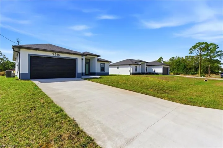 Prairie-style home with an attached garage, concrete driveway, a front yard, and stucco siding