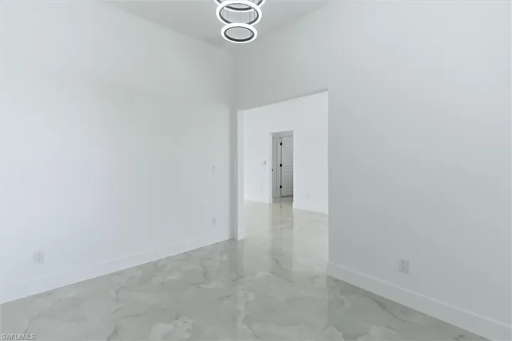 Unfurnished room featuring a high ceiling and suspended lighting