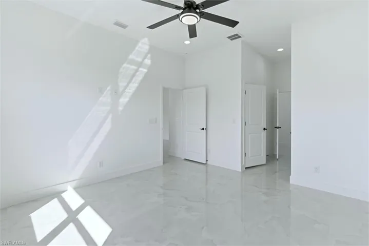 Additional living space featuring a ceiling fan and light marble finish floors