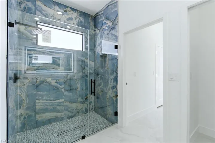 Full bathroom with a marble finish shower and baseboards