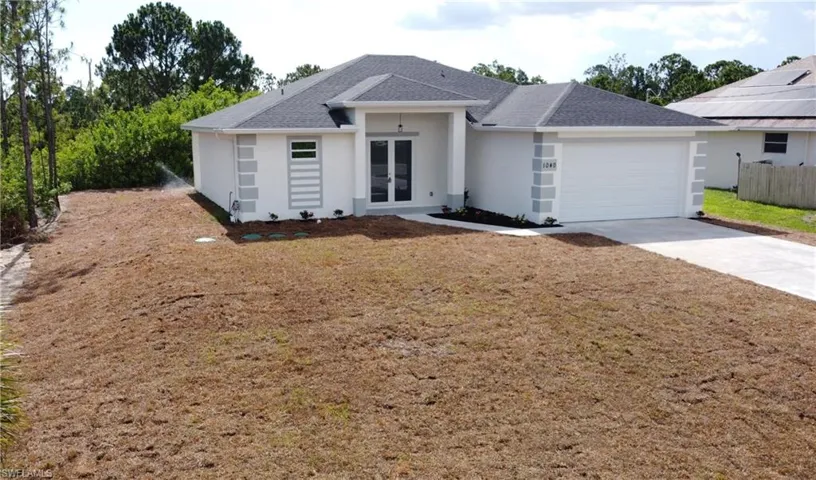 Ranch-style home with a garage, french doors, and solar panels