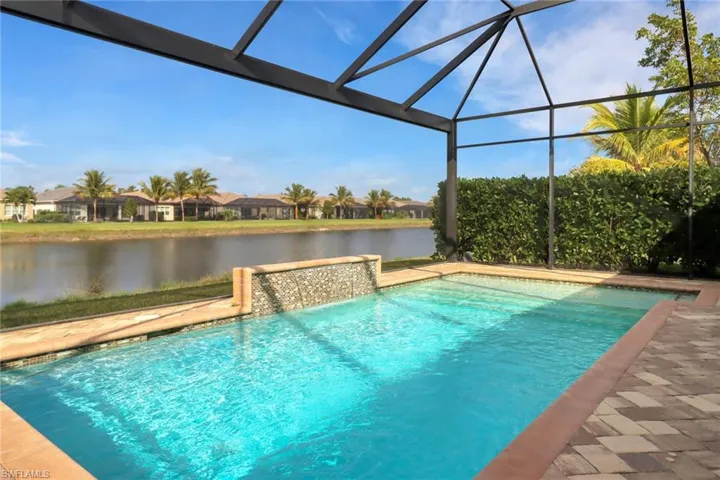 View of pool featuring a water view and glass enclosure