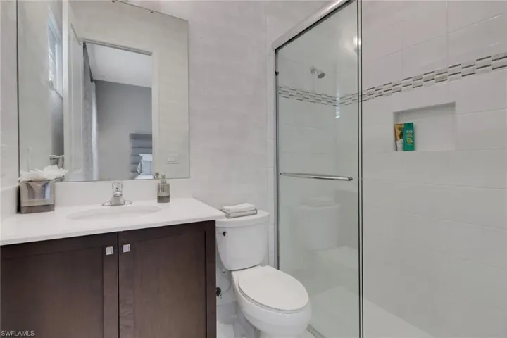 Bathroom featuring a shower with door, vanity, and toilet