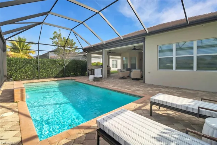 View of pool with a patio, an outdoor hangout area, ceiling fan, and glass enclosure