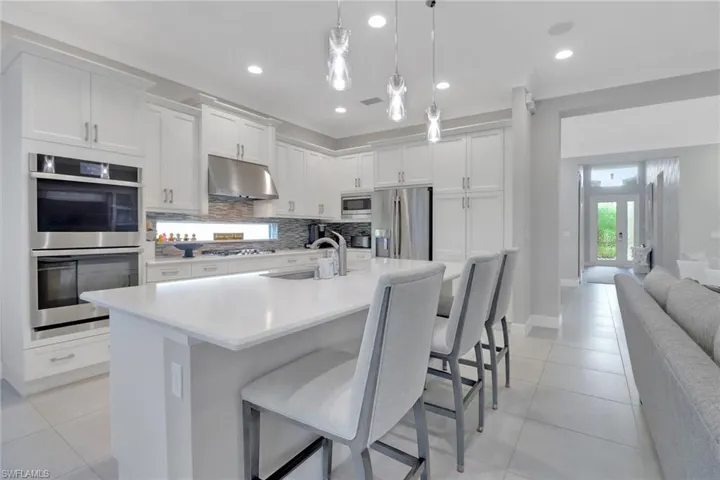 Kitchen with appliances with stainless steel finishes, sink, a breakfast bar area, white cabinets, and hanging light fixtures