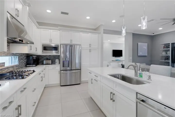 Kitchen with stainless steel appliances, white cabinetry, sink, and pendant lighting