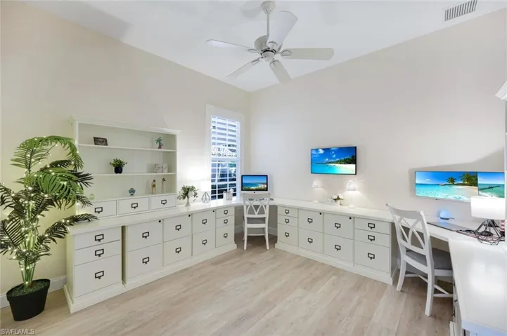 Dedicated workspace featuring extensive built-in cabinetry, wood-finish flooring, and a ceiling fan.  This fourth bedroom is currently set up as a home office.