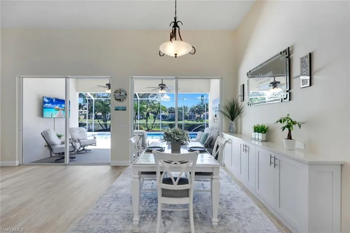 Dining area featuring high ceilings, wood-finish flooring, and expansive sliding glass doors opening to a screened lanai overlooking your private pool.