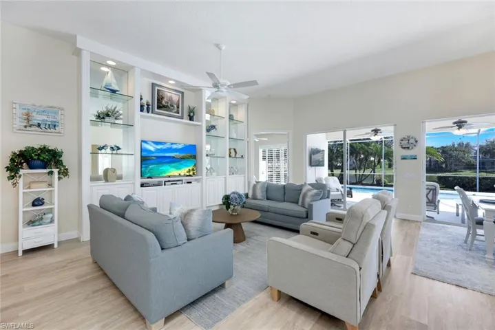 Open-concept living area featuring wood-finish flooring and a built-in media center with illuminated glass shelving