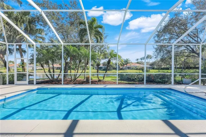 Screen-enclosed heated saltwater swimming pool featuring a tiled waterline, integrated steps, and a surrounding patio deck