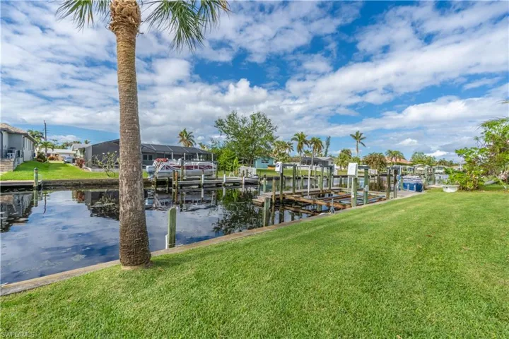Dock area with a lawn, boat lift, a water view, and a residential view