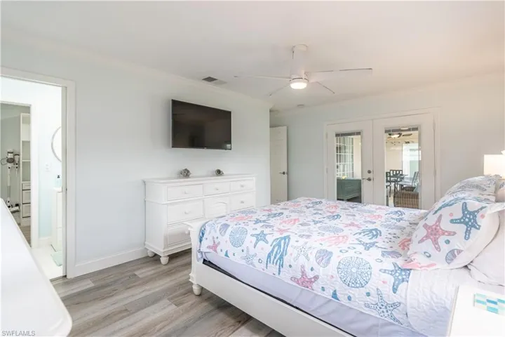 Bedroom with french doors, light wood-style floors, ornamental molding, ceiling fan, and access to outside