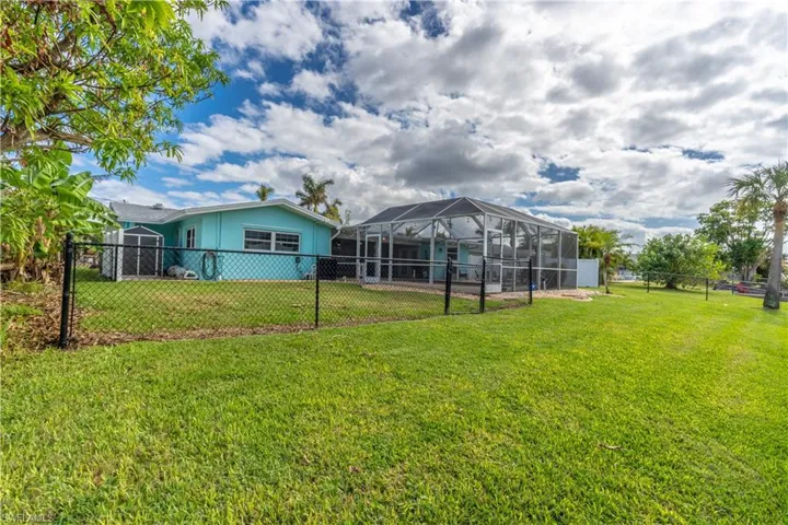 Rear view of house with a fenced backyard, glass enclosure, and a sunroom