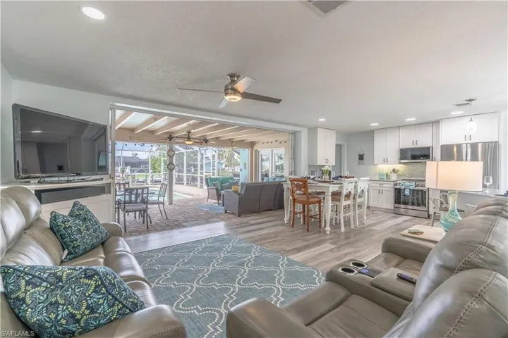 Living room with beam ceiling, light wood finished floors, plenty of natural light, a sunroom, and recessed lighting