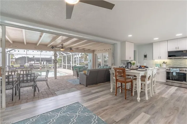 Dining space with a sunroom, ceiling fan, healthy amount of natural light, light wood finished floors, and beam ceiling