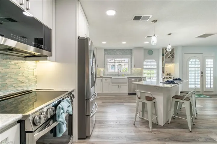 Kitchen featuring appliances with stainless steel finishes, white cabinets, decorative light fixtures, recessed lighting, and light stone countertops