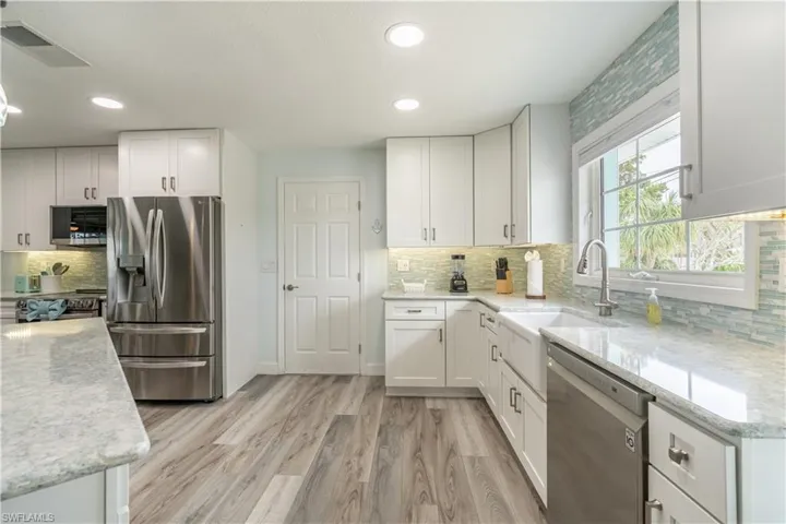 Kitchen with appliances with stainless steel finishes, white cabinets, tasteful backsplash, and recessed lighting