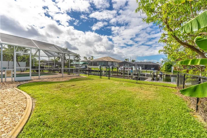 Fenced yard featuring glass enclosure, a swimming pool, a sunroom, and a water view