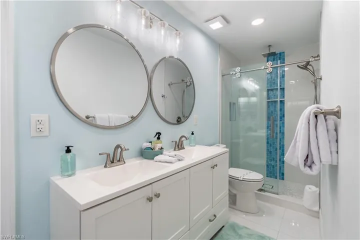 Bathroom featuring double vanity, a stall shower, and light tile patterned flooring