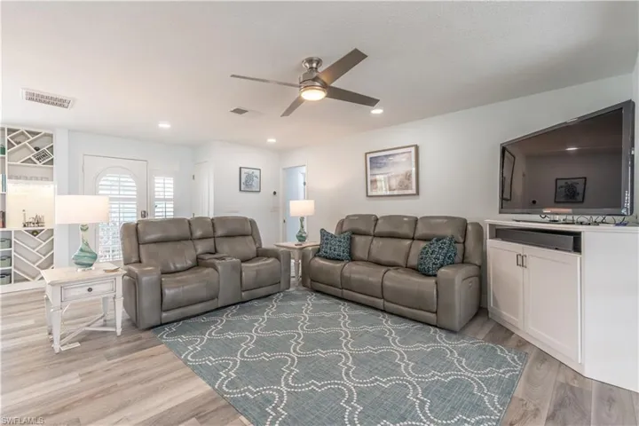 Living room with light wood-style flooring, ceiling fan, and recessed lighting