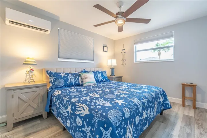 Bedroom featuring a wall unit AC, light wood-style floors, and a ceiling fan