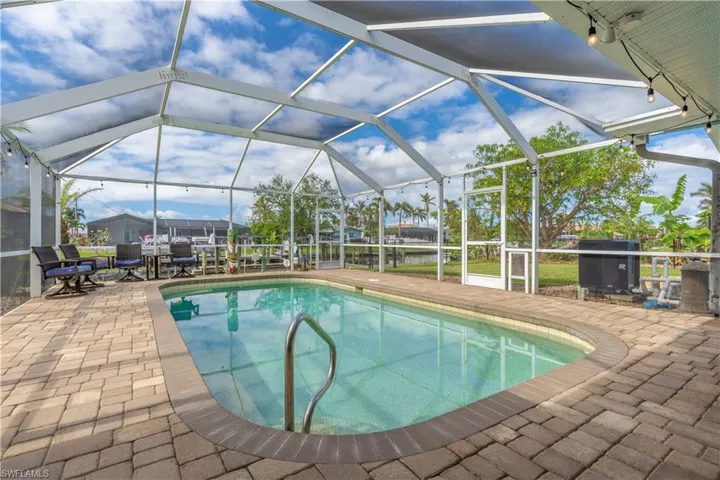 Outdoor pool featuring a sunroom, glass enclosure, area for grilling, and a patio area